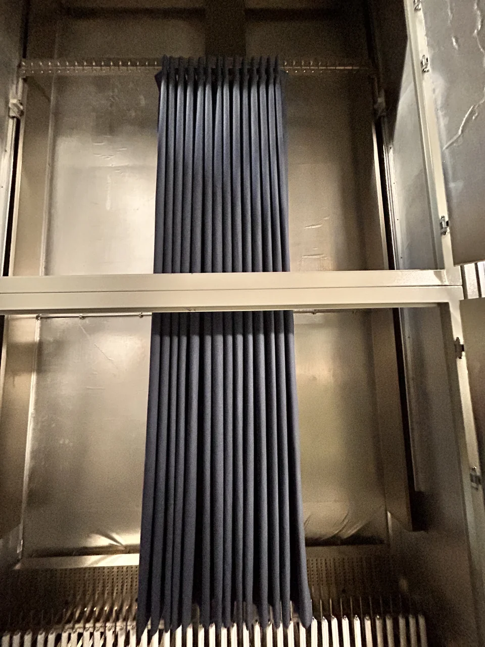 Dark blue curtains hung at full length inside the AAA Blinds heat-setting cabinet, with vertical folds carefully aligned