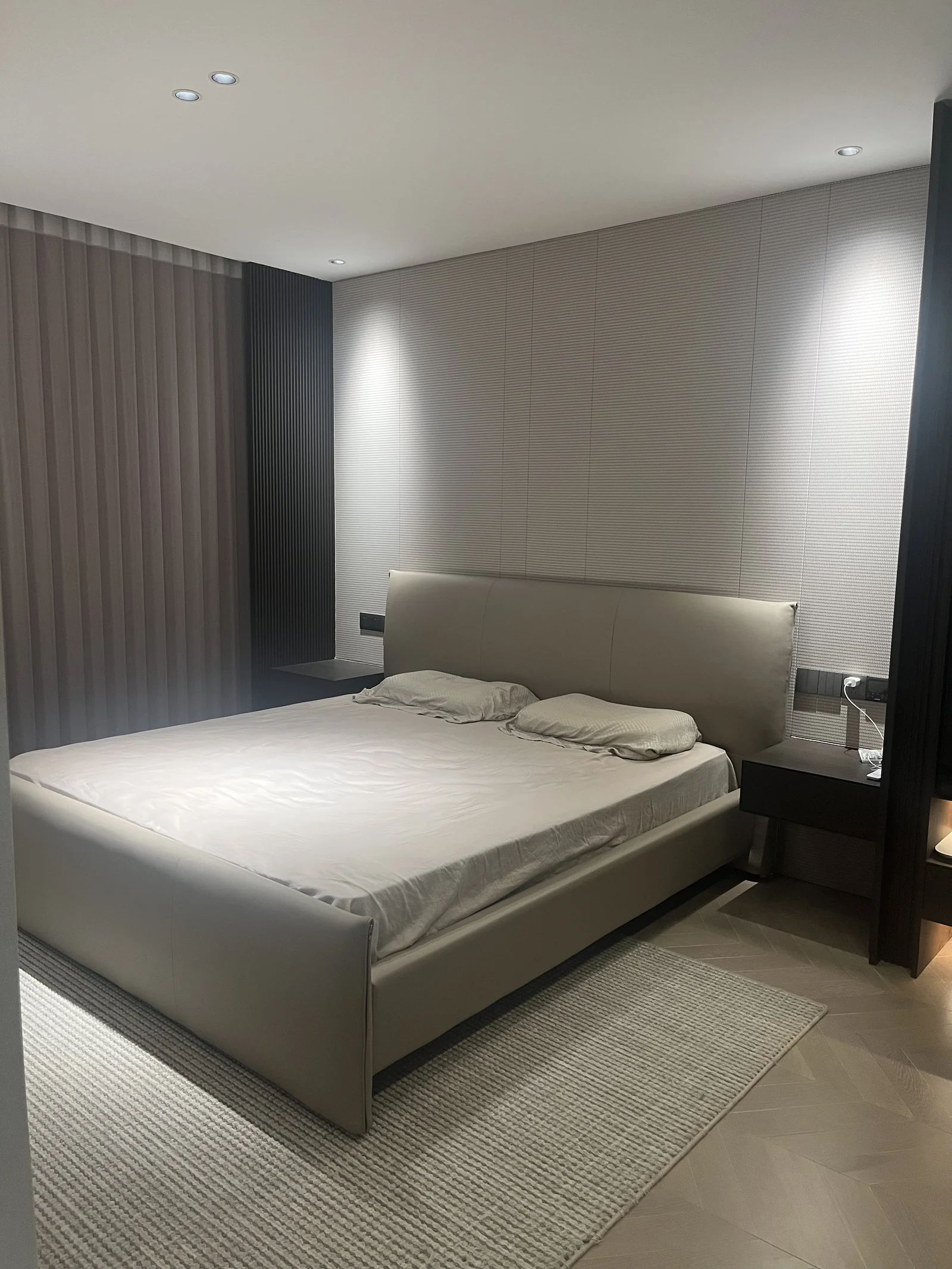 Full-height grey drapery beside a bed in a neutral bedroom