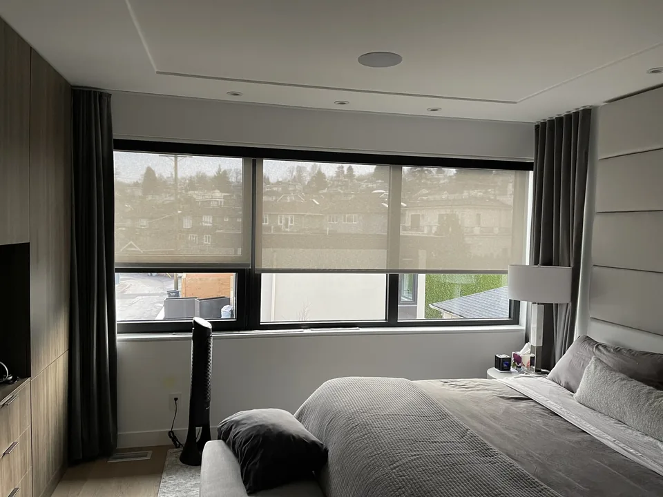 Roller shades sit close to the glazing while side curtains add a soft frame around the bedroom windows