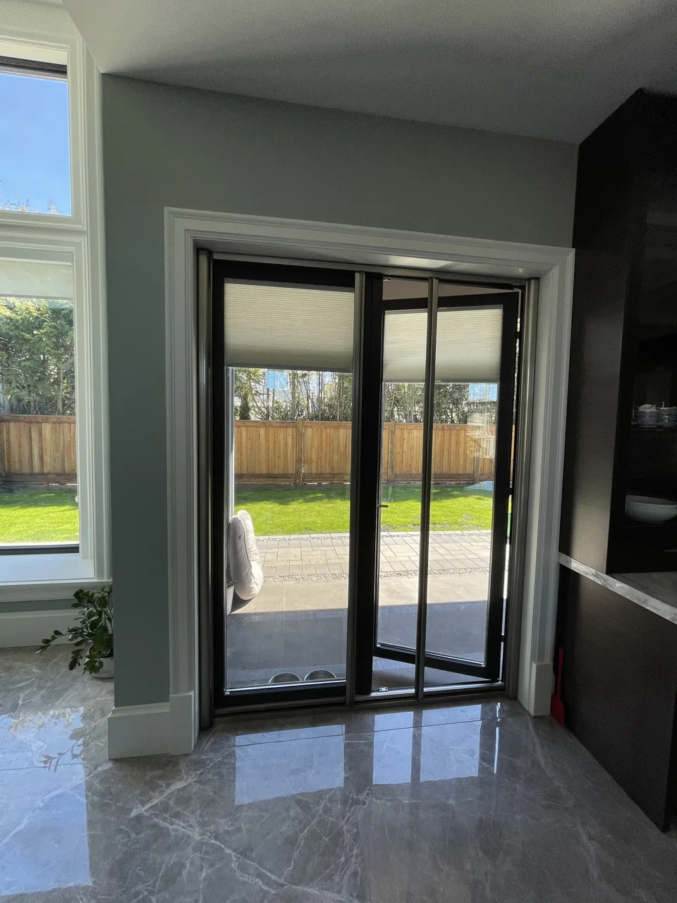 A slim screen frame sits inside a dark-framed garden doorway
