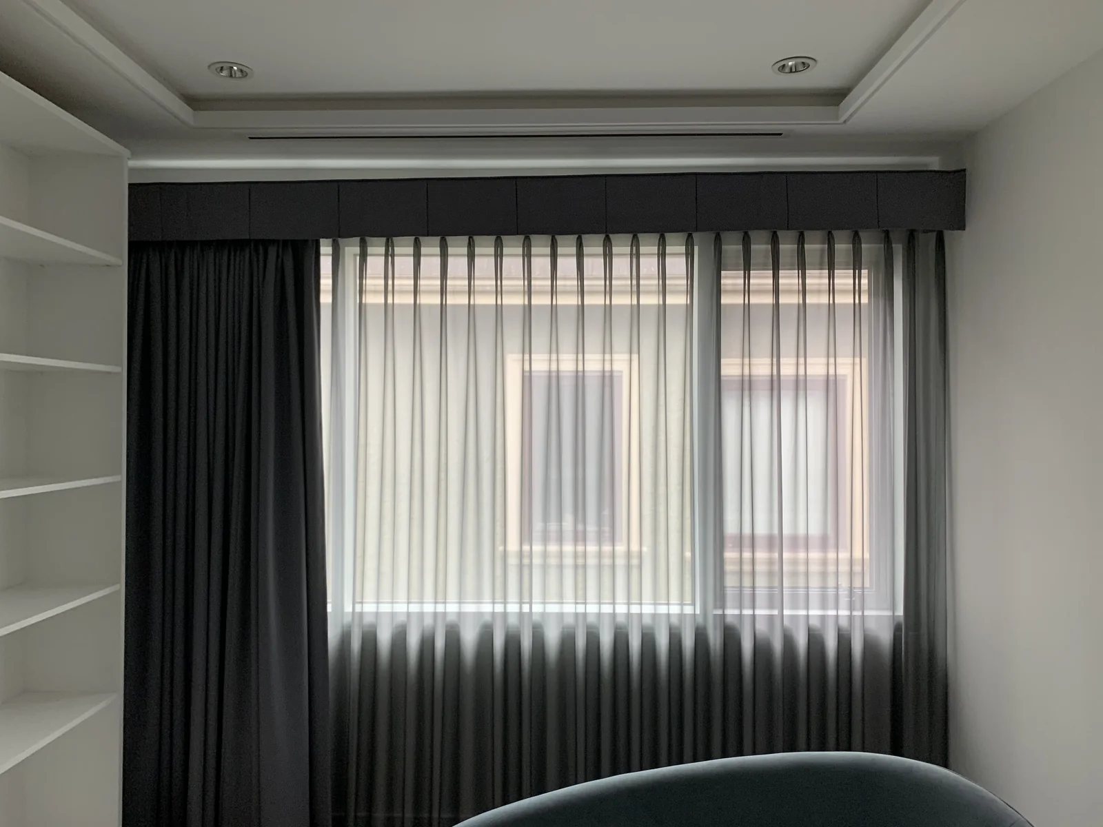 Light-filtering sheers across a window with charcoal drapery and a matching pelmet