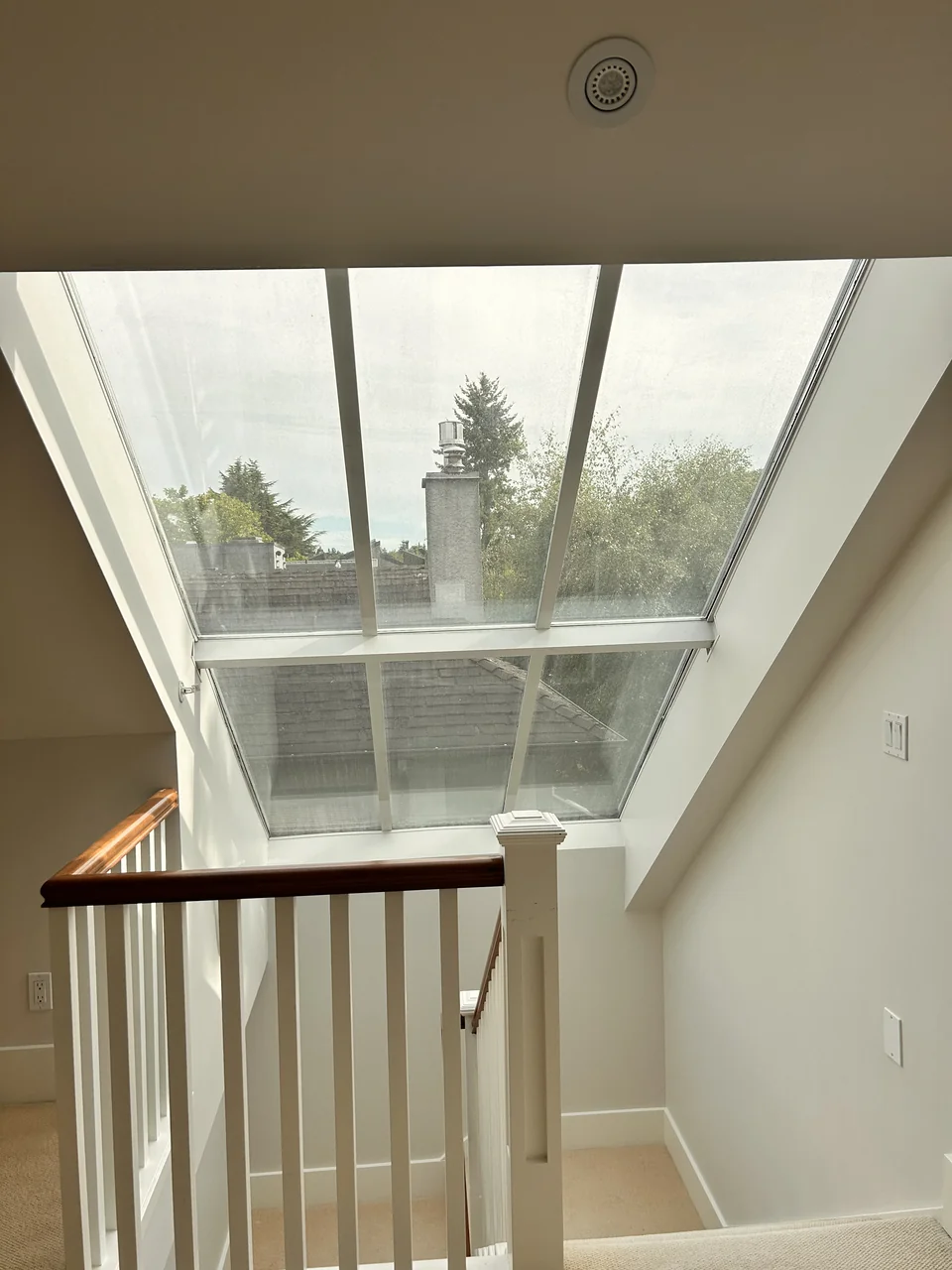 Uncovered six-pane skylight above a white staircase with a timber handrail