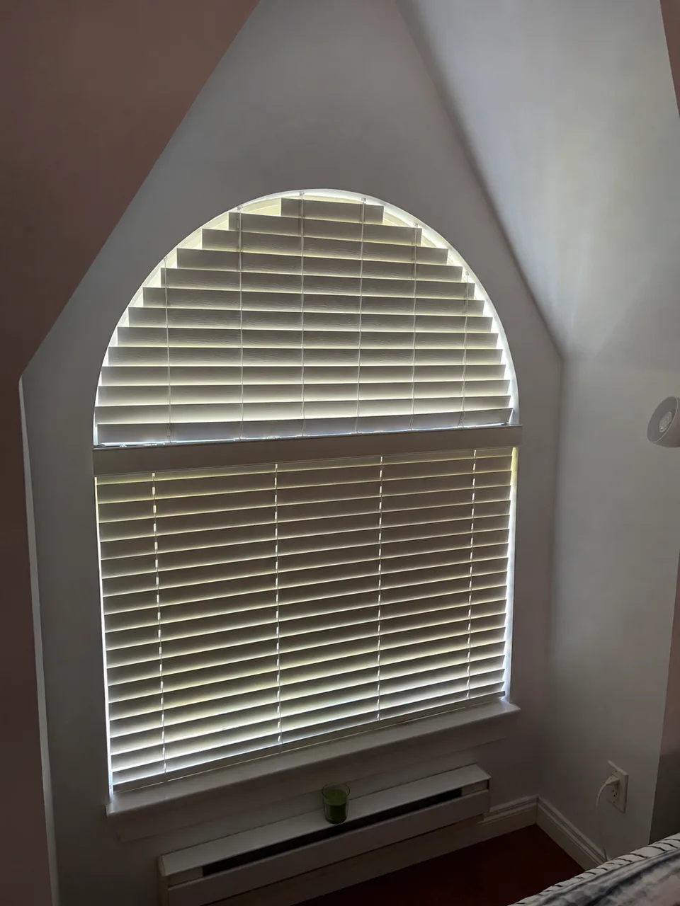 Horizontal blind slats follow the arched upper window above a separate lower blind